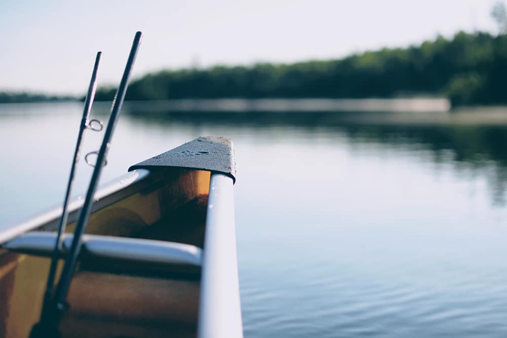 Pond with the front of a boat with a fishing pole leaning against the bow